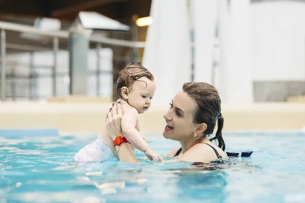 母と彼女の赤ちゃんの娘はウォーターパークのプールで泳ぐ 最初の水泳 — ストック写真