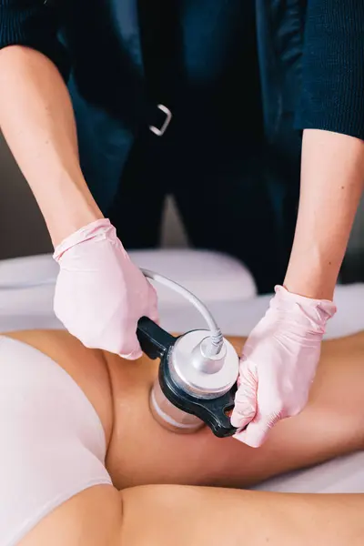 stock image Woman, a beautician doing radiofrequency RF treatment on her client's thigh in a beauty salon. Skin tightening, body contouring, and reducing wrinkles.