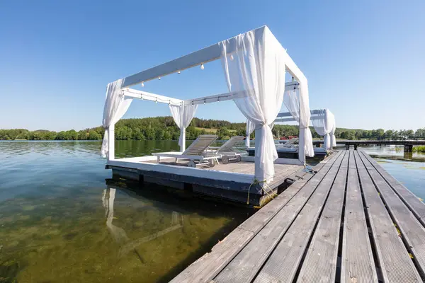 stock image White cabana with lounge chairs by tranquil lake. Kashubia region in Poland.