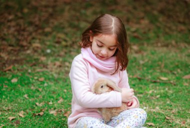 happy little girl with a rabbit in her hands in the park