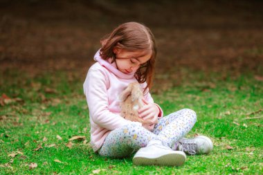 happy little girl with a rabbit in her hands in the park