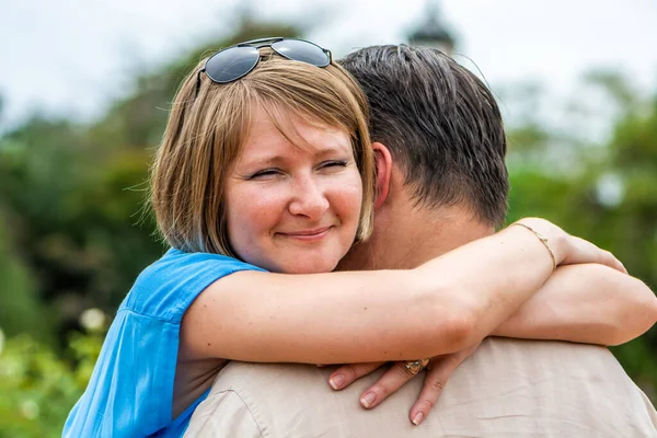 在公园里拥抱丈夫的年轻而情绪化的女人 — 图库照片