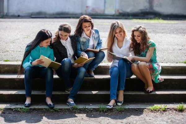 一群女学生坐在大学的院子里 手里拿着书本 — 图库照片
