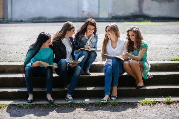 大学の中庭に本を持って座っている女子学生のグループは — ストック写真