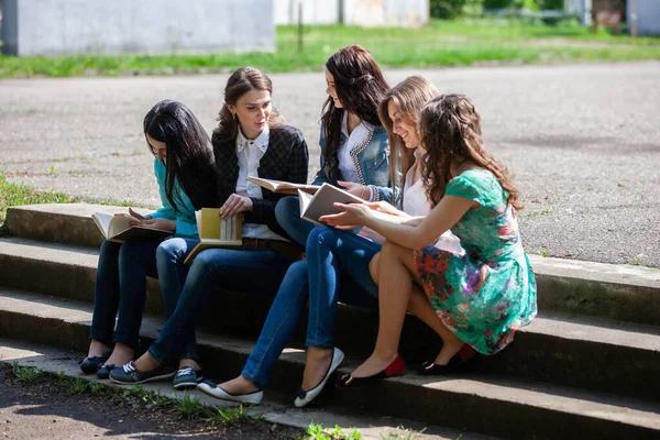 一群女学生坐在大学的院子里 手里拿着书本 — 图库照片