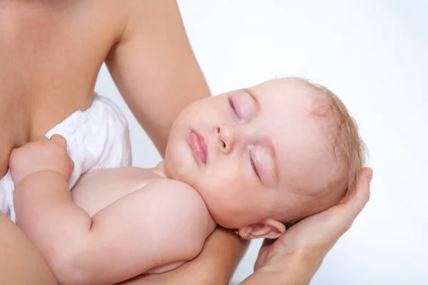 赤ん坊は母の手の上で軽い背景で眠り — ストック写真