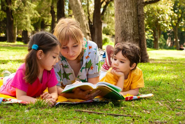 草の上の公園で楽しい家族が本を読んで — ストック写真
