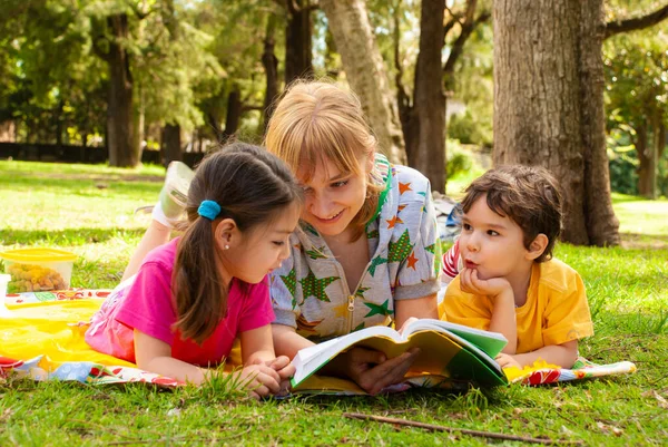 公园里快乐的一家人在草地上看书 — 图库照片