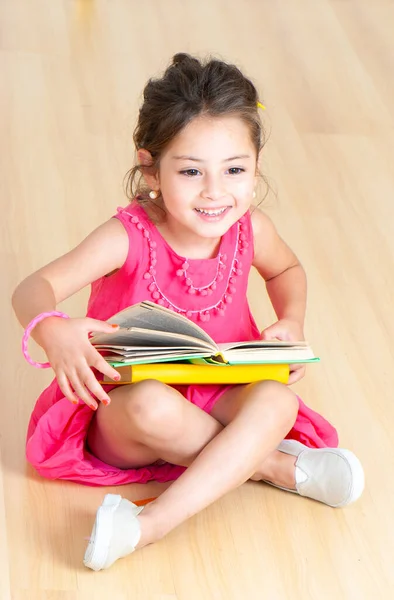 在幼儿园的地板上坐着一本书的女孩 — 图库照片