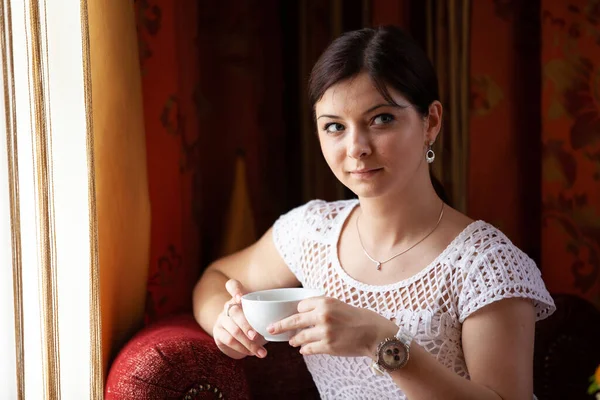 彼女の手にマグカップとカフェで幸せな若い女の子の肖像画 — ストック写真