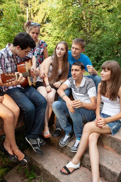 Bir grup genç, bir gitarla parkta dinleniyor.