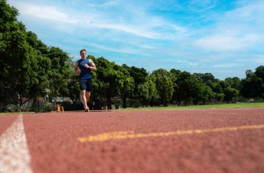 Genç sporcu stadyumdaki koşu bandında koşuyor.