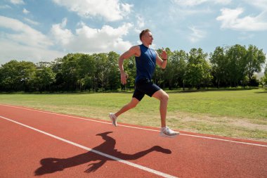Genç sporcu stadyumdaki koşu bandında koşuyor.