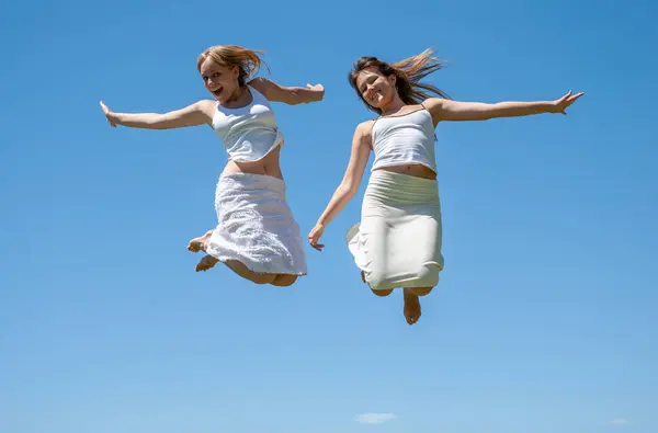 Happy Girls Jumping Sky Image En Vente