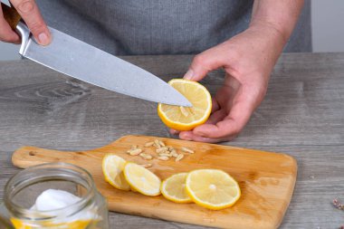 Bir kadının eli bir limonu bıçakla keser ve soyar. Koruma için hazırlanıyor. Yakın plan..