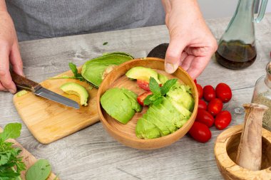 Avokado soyulmuş ve aşçının elinde çıkarılmış bir çukur. Avokado servise hazır..