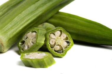 Yeşil taze bamya. Beyaz arka planda tüm kapsüller ve parçalar var. Makro.