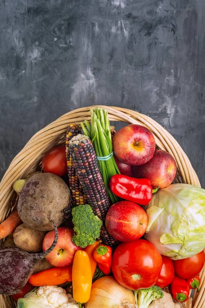 Basket full of vegetables and fruits on  gray background, top view. Autumn and harvest time. Space for text.