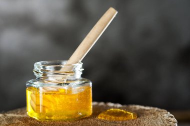 Cam bir kavanozda şeffaf bal ve ağaç kesiği.