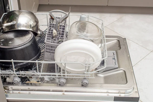 open dishwasher with dirty dishes, plates, spoons, forks, cutlery, dishwasher tray.