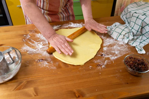 An elderly woman prepares pie from the dough. Close-up hands hold a rolling pin.