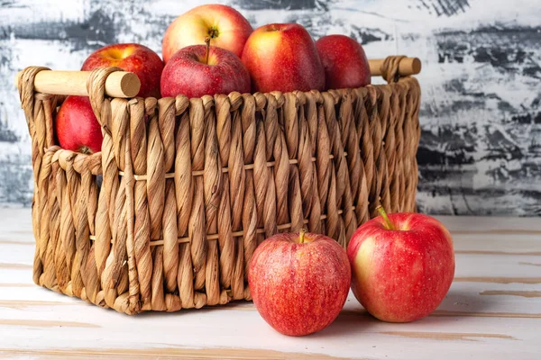 Two apples on the background of a wicker basket full of ripe apples.