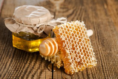 Bal petekleri ve taze şeffaf bal, cam bir kavanozda, ahşap bir masada, Dipper ile..