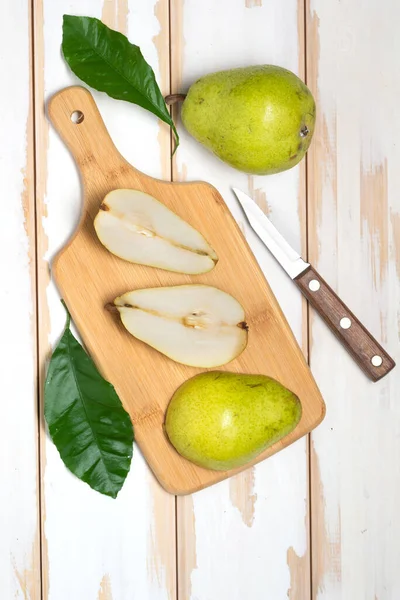 slices of pears on a cutting board with  knife. White boards, top view.