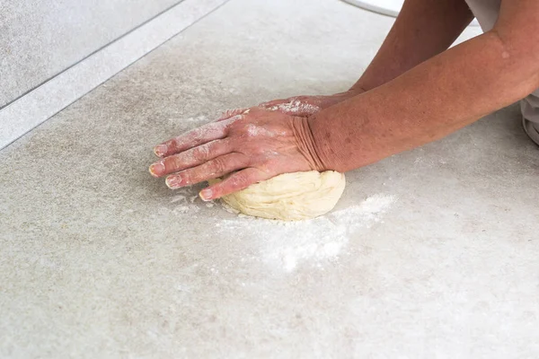 woman\'s hands knead the dough for making pizza or pies.