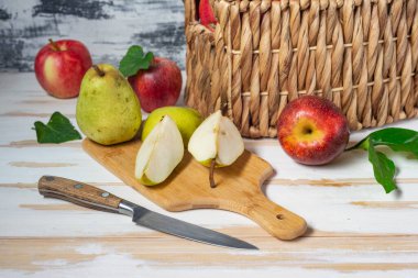 Armut ve elmalı sepet. Armut dilimleri ve bıçakla tahta kesmek..