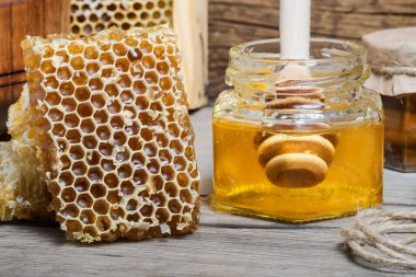 Bal petekleri ve cam kavanozda taze şeffaf bal ve ahşap masa üzerinde dereotu..