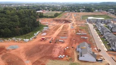 Yeni evleri ve yeni inşaatı olan bir inşaat alanı. Kırmızı kil ve iletişim. Ekipman ve borular. Yukarıdan görüntüle.