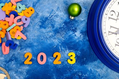 Yeni yıl kompozisyonu 2023 ve saat ile. Mavi arka planda Noel süslemeleri. Yukarıdan bak. Metin için boşluk.