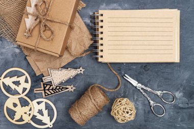 Noel hazırlığı. El yapımı hediyeler. Düz kağıt, turnike ve gri bir masada kutu. Mesaj için not al. Yukarıdan bak. Metin için boşluk.