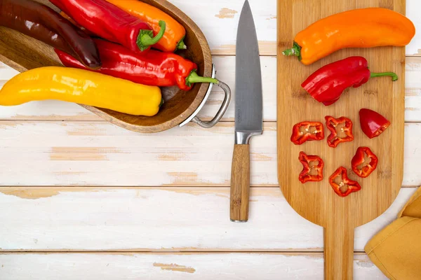 stock image Fresh sweet pepper (bell pepper) on a cutting board with a knife. Chopped pepper pieces are ready to cook. Light wooden table, top view. Space for text.