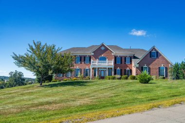 Güzel peyzajı ve çimenliği olan geleneksel bir Amerikan aile evi. Mavi gökyüzünün altında güneşli bir günde yaz manzarası.