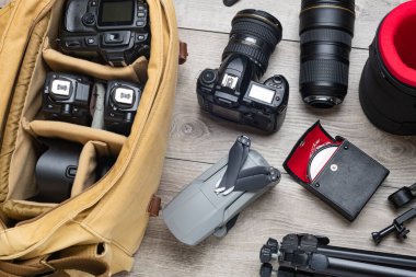 Profesyonel fotoğraf ekipmanları, İHA 'lar, tripod' lar ve gri masadaki çantalar. Yukarıdan görüntüle.