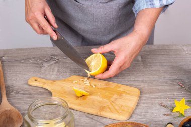 Kadın eli kesme tahtasındaki bıçakla limonun tohumlarını kesip çıkarıyor.