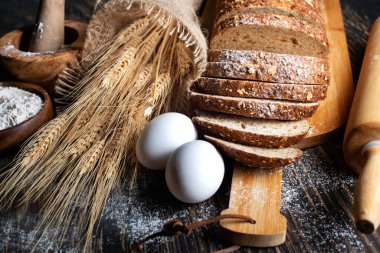 Bir somun çavdar ekmeği, buğday kulakları, yumurta ve bir kase un. Yakın plan..