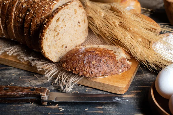 Wheat flour, sliced bread  with sesame seeds, wheat ears and straw on an old wooden background