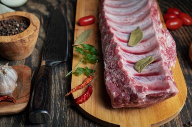 Biberli çiğ pirzola, körfez yaprakları ve baharatlar. Siyah bir arkaplanda.