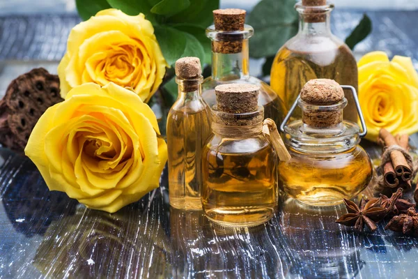 Cosmetic and aromatic rose oil in bottles. Yellow roses on a blue table.