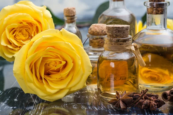 aromatic and Cosmetic rose oil in bottles. Yellow roses on a blue table.