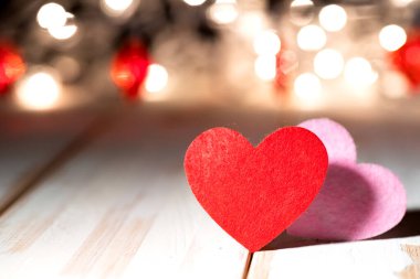 two red hearts on wooden table against defocused bokeh light background. Love, valentine's day concept.