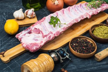 Fresh raw lamb spare ribs with spices and herbs on Black wooden table.