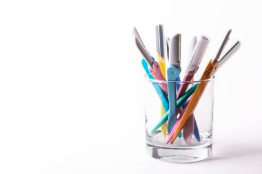 Set of multi-colored women's shaving razors in glass isolated on white background. Space for text.