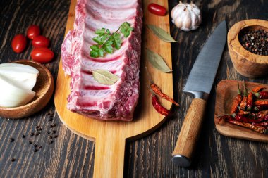 Fresh raw lamb spare ribs with spices and herbs. Black wooden background.