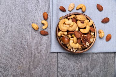various nuts in a wooden bowl on gray surface. space for text