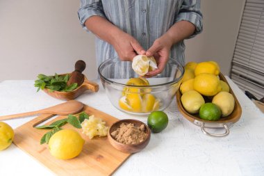 woman in the kitchen cuts lemons to make lemonade.