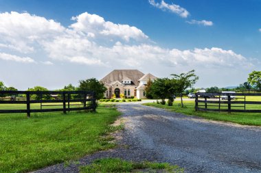 Front view of brick home in suburban area with spacious lawn and trees with rubble path and private parking